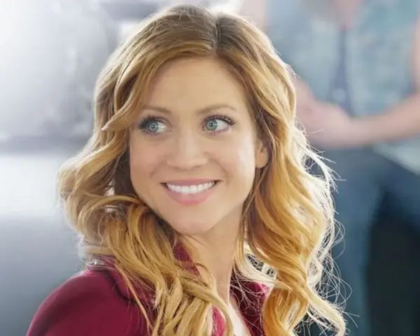 Brittany Snow lächelt in einem roten Blazer. Ein Blick auf ihre Rolle in Filmen von Brittany Snow.