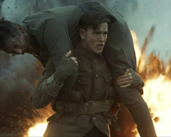 Harris Dickinson trägt einen verwundeten Kameraden durch Explosionen. Ein dramatischer Moment aus seinen Filmen.