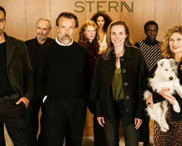 Ensemble der Fernsehserie "Besetzung von Berlin" posiert lächelnd mit einem Hund.