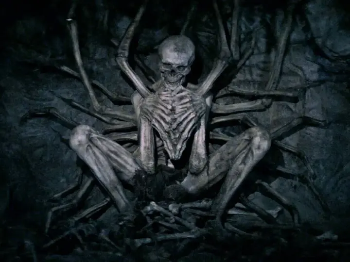 Ein skelettartiges Wesen, der leere Mann, sitzt in einer dunklen Höhle, umgeben von knochigen Gliedmaßen.