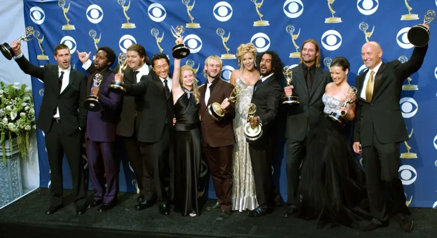 Die Besetzung von Lost feiert Emmy-Erfolge. Die Schauspieler posieren mit ihren Trophäen vor einem blauen Banner mit dem CBS-Logo.