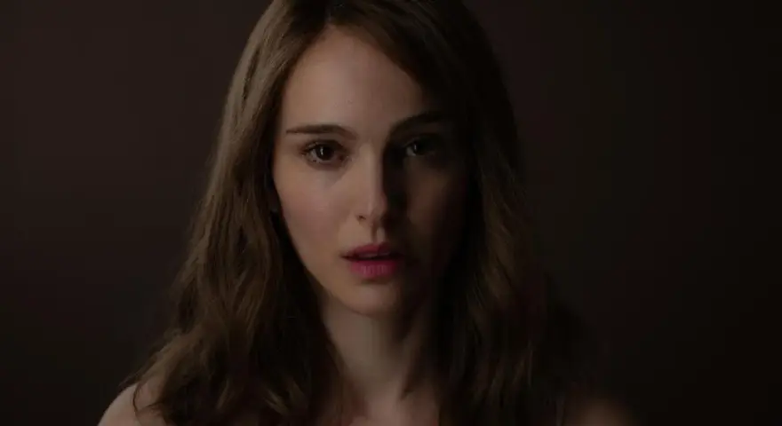Natalie Portman, bekannt aus vielen Filmen, blickt nachdenklich in die Kamera. Ihr Gesicht ist im Schatten, nur ihre Augen und Lippen sind beleuchtet.