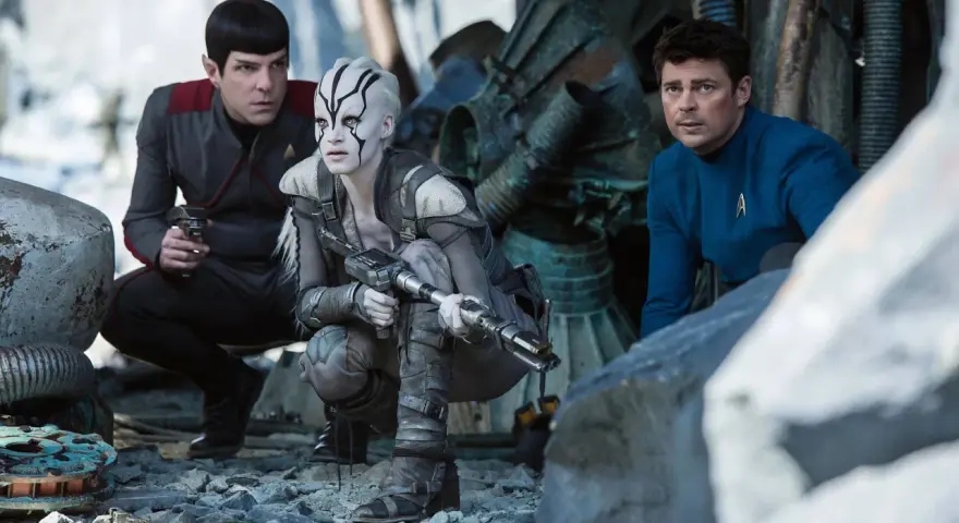 Die Besetzung von Star Trek 2009: Spock, eine Kriegerin mit Kriegsbemalung und Dr. McCoy kauern im Trümmerfeld.