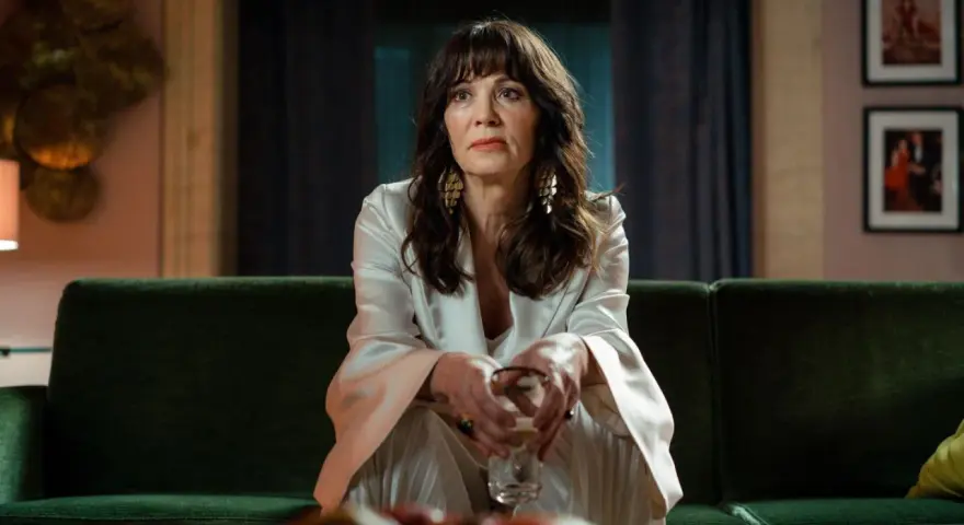 Iris Berben in einem eleganten Outfit, nachdenklich auf einem grünen Sofa sitzend. Ein Blick, der an ihre vielen Filme erinnert.