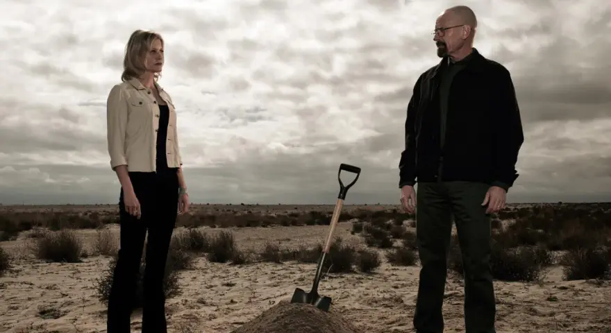 Die Besetzung von Breaking Bad: Walter und Skyler stehen in der Wüste, eine Schaufel liegt neben einem frisch aufgeworfenen Erdwall.