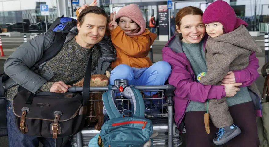 Glückliche Familie am Flughafen, bereit für eine Reise, die sich anfühlt wie eine millionen minuten Vorfreude.