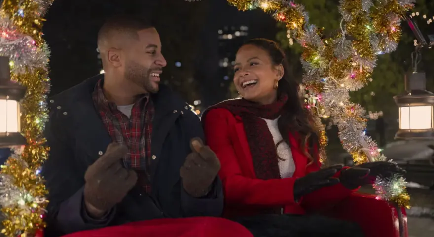 Ein glückliches Paar in einer Kutsche, geschmückt mit Lichterketten. Sie lachen und zeigen aufeinander. Vielleicht ein Versprechen: "Meet me next Christmas.
