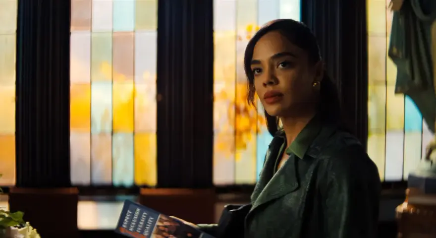 Tessa Thompson in einem grünen Mantel, mit einem Heft in der Hand, vor einem bunten Fenster. Ein Blick auf ihre Rolle in Filmen von Tessa Thompson.