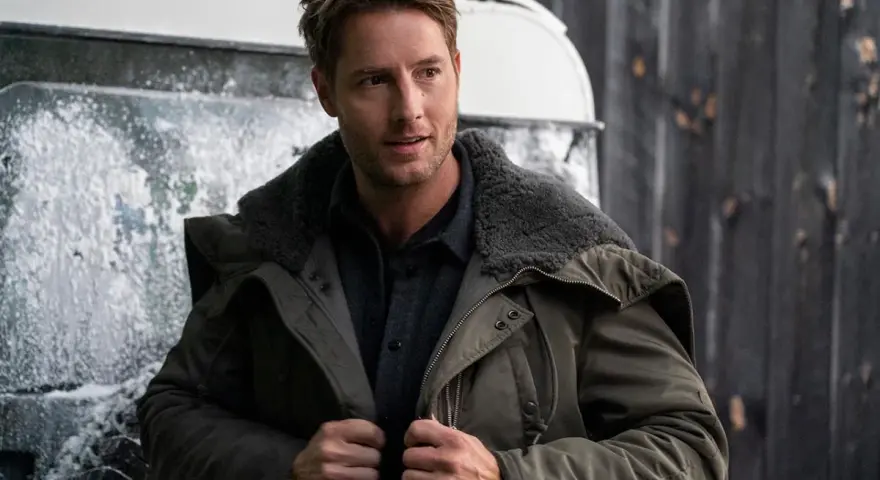 Mann in Winterjacke, inspiriert von "The Noel Diary", steht vor einer verschneiten Kulisse.