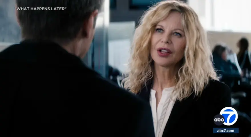 Meg Ryan spricht mit einem Mann, während im Hintergrund Menschen sitzen. Was passiert später?