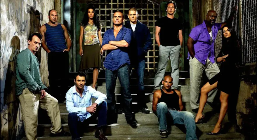 Die Hauptbesetzung von Prison Break posiert auf Treppen vor einem Gittertor.