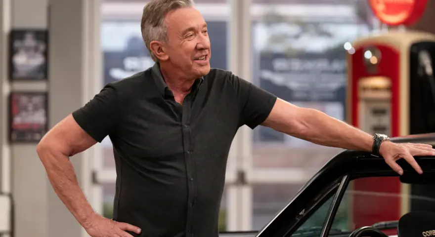 Tim Allen, bekannt für seine Filme und Serien, lehnt lässig an einem Auto. Im Hintergrund eine alte Zapfsäule.