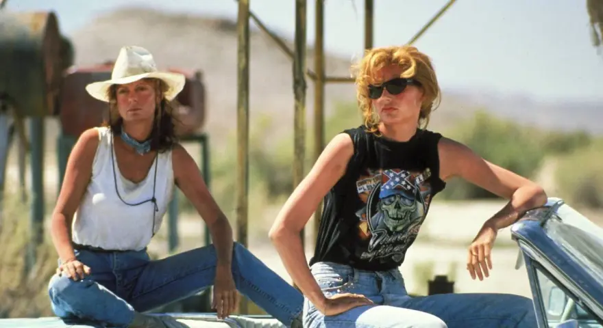 Die besetzung von Thelma & Louise: Geena Davis mit Cowboyhut und weißem Top, Geena Davis mit Sonnenbrille und schwarzem Shirt mit Totenkopf.