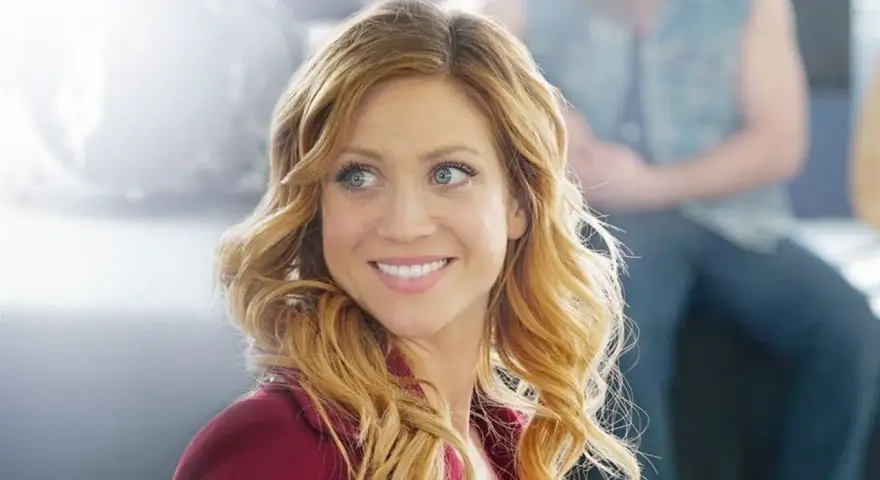 Brittany Snow lächelt in einem roten Blazer. Ein Blick auf ihre Rolle in Filmen von Brittany Snow.
