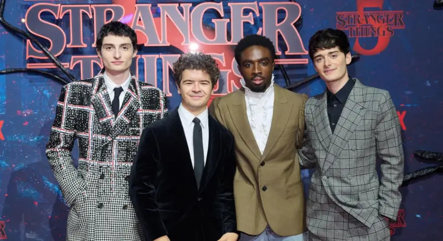 Die Besetzung von Stranger Things posiert vor dem Logo der Serie.