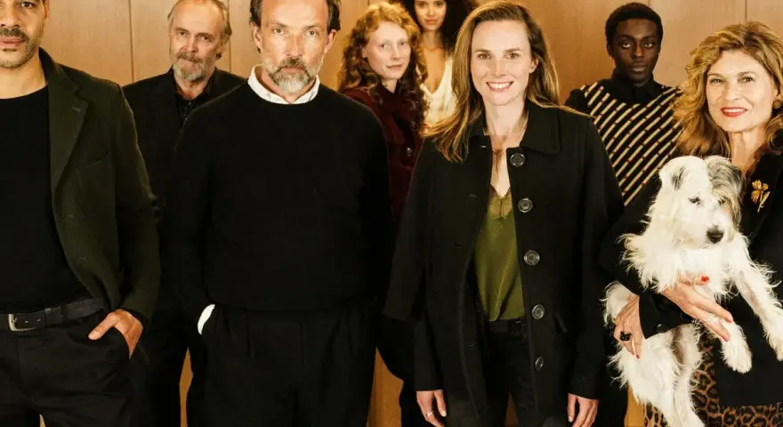 Ensemble der Fernsehserie "Besetzung von Berlin" posiert lächelnd mit einem Hund.