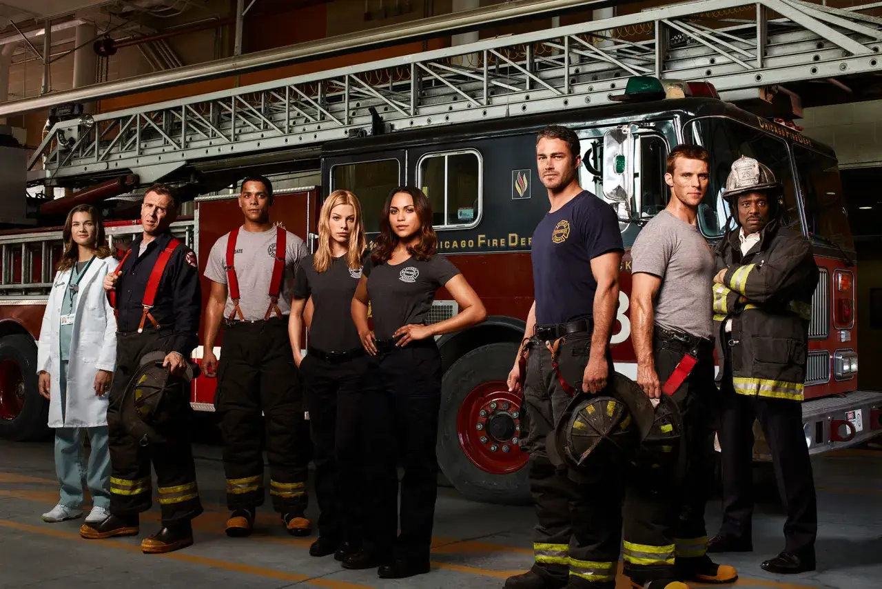 Die Besetzung von Chicago Fire posiert vor einem Feuerwehrauto.