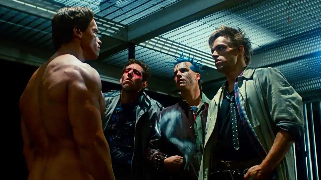 Arnold Schwarzenegger als Terminator trifft auf eine Gruppe von Punks. Die Besetzung von Terminator zeigt Arnold von hinten, während die Punks ihn mit misstrauischem Blick mustern.