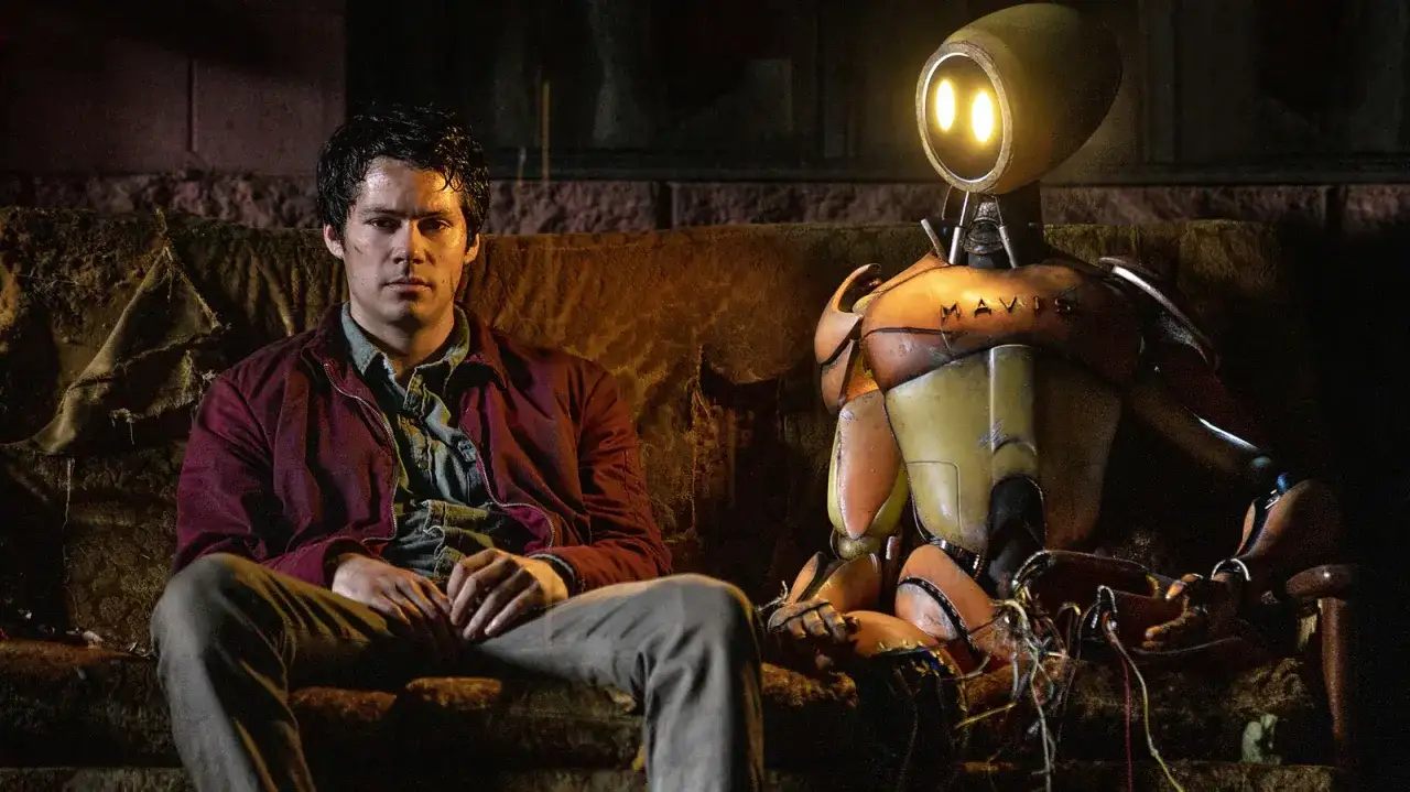 Ein Mann und ein Roboter namens MAVIS sitzen auf einer Couch. Eine ungewöhnliche Freundschaft, die zeigt, dass Liebe auch zwischen Menschen und Monstern entstehen kann.
