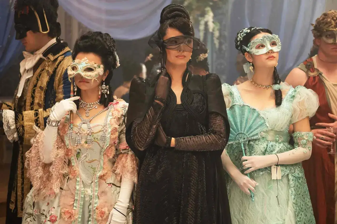 Drei Damen in prächtigen Kleidern und Masken bei einem Ball. Die Szene könnte aus Bridgerton Staffel 4 stammen, voller Geheimnisse und Romantik.