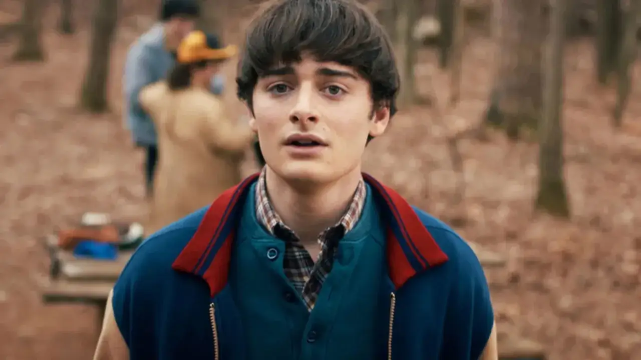 Noah Schnapp in einem Wald, mit Freunden im Hintergrund. Ein Blick, der an seine Rollen in Filmen erinnert.