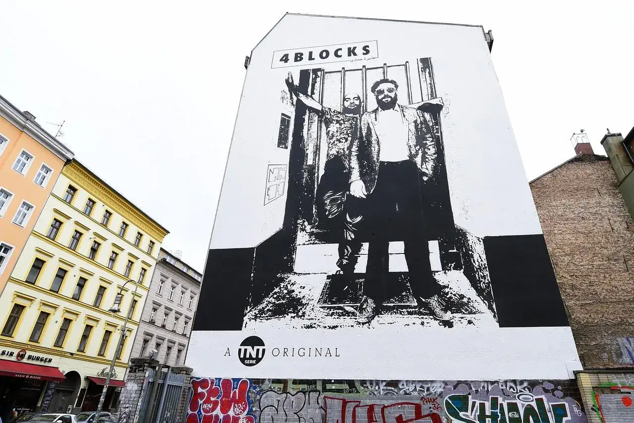 Großes Wandbild mit zwei Männern, die vor Gittern stehen. Über ihnen steht