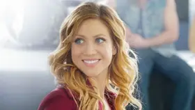 Brittany Snow lächelt in einem roten Blazer. Ein Blick auf ihre Rolle in Filmen von Brittany Snow.