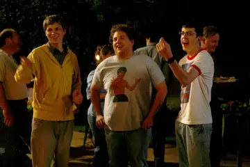Die Besetzung von Superbad feiert eine Party. Michael Cera, Jonah Hill mit Bruce Lee T-Shirt und Christopher Mintz-Plasse lachen ausgelassen.