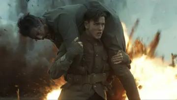 Harris Dickinson trägt einen verwundeten Kameraden durch Explosionen. Ein dramatischer Moment aus seinen Filmen.