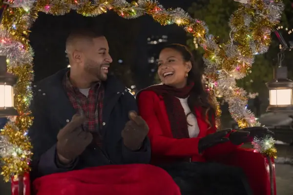 Ein glückliches Paar in einer Kutsche, geschmückt mit Lichterketten. Sie lachen und zeigen aufeinander. Vielleicht ein Versprechen: "Meet me next Christmas.