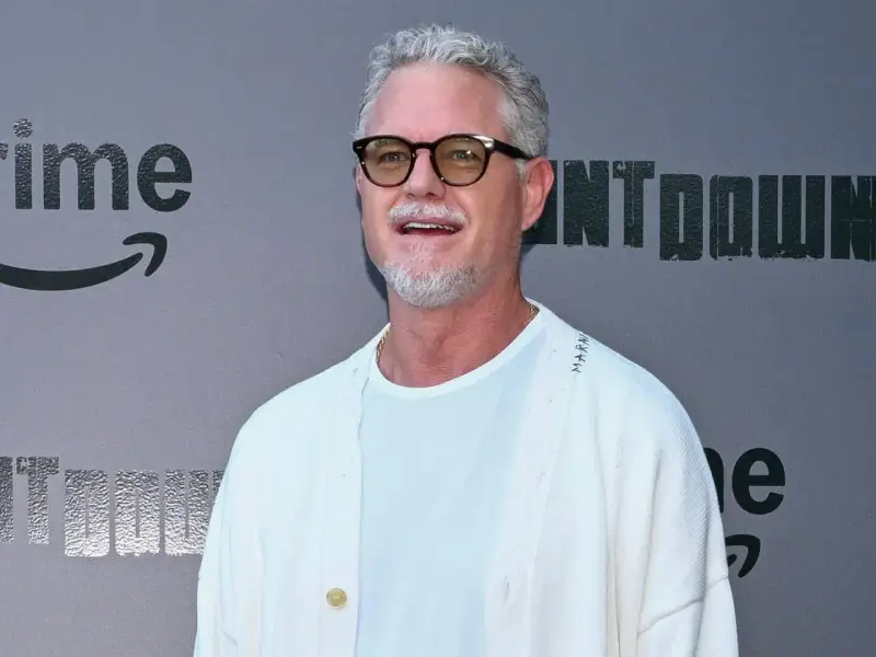 Eric Dane, bekannt für seine Rollen in Filmen und Serien, trägt eine Brille und ein weißes Outfit vor einem grauen Hintergrund mit dem Amazon Prime Logo.