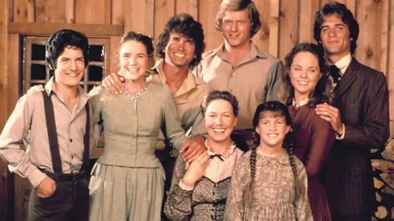 Die Besetzung von Unsere kleine Farm: Eine glückliche Familie posiert vor einer Holzwand.